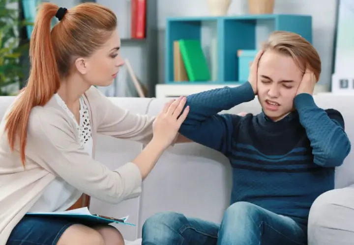 Terapeutaka wspierająca nastolatka z depresją, który zakrywa uszy.