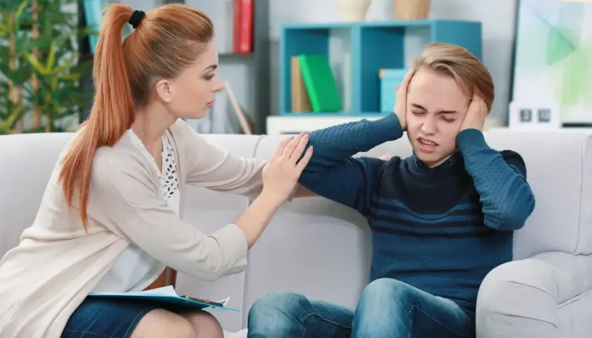 Terapeutaka wspierająca nastolatka z depresją, który zakrywa uszy.